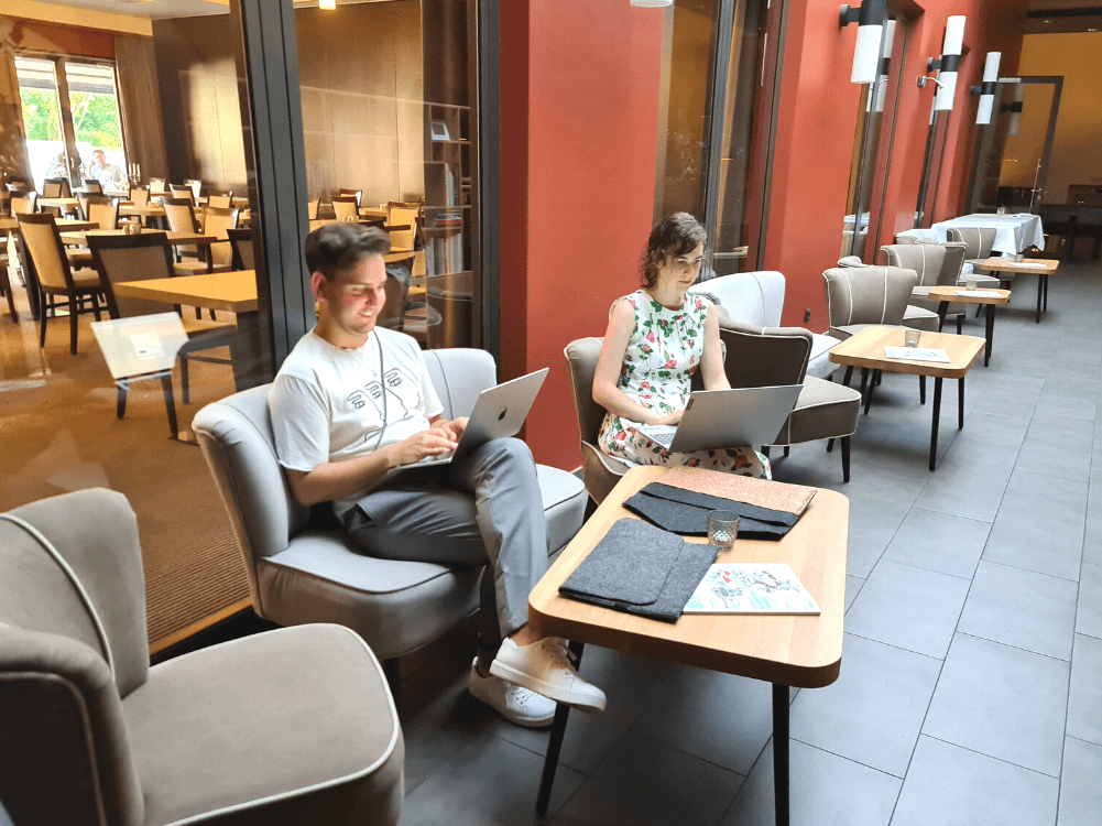 Zwei Tagungsteilnehmer mit Laptops in der Hotellobby