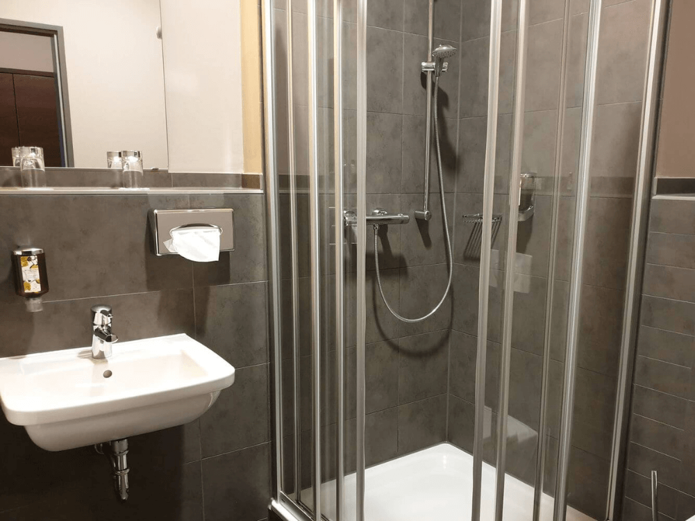Badezimmer mit Waschbecken, Spiegel und Duschkabine