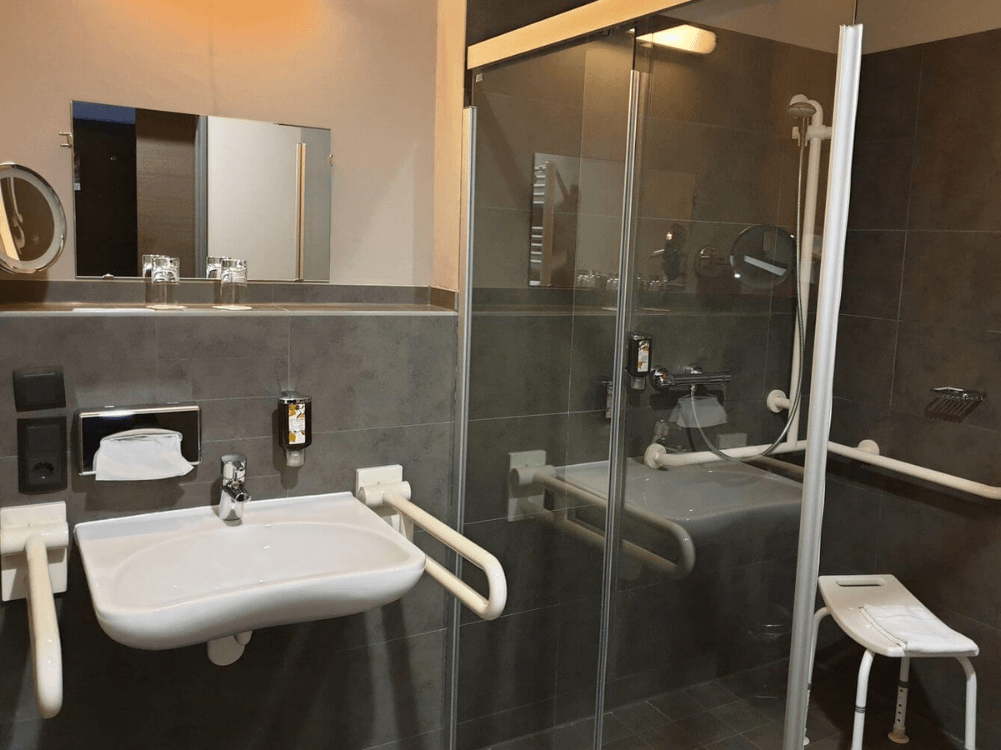 Bad mit barrierefreier Duschkabine, Waschbecken, Hocker und Spiegel