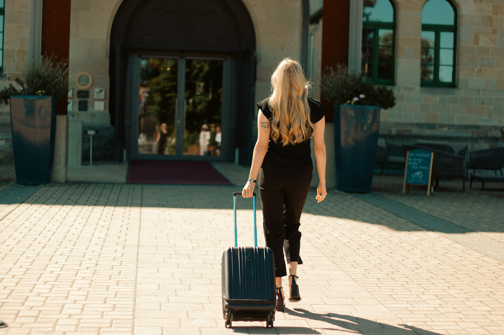 Frau mit Koffer spaziert ins Hotel