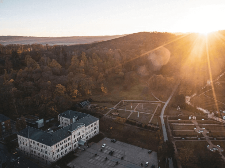 Ansicht von oben auf Hotelgebäude, Parkplatz und Landschaft bei Sonnenuntergang