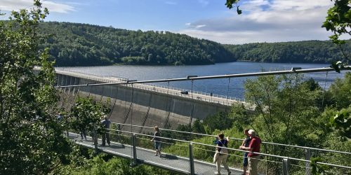 Hängebrücke vor der Staumauer der Rappbodetalsperre mit Bergen und Stausee im Hintergrund