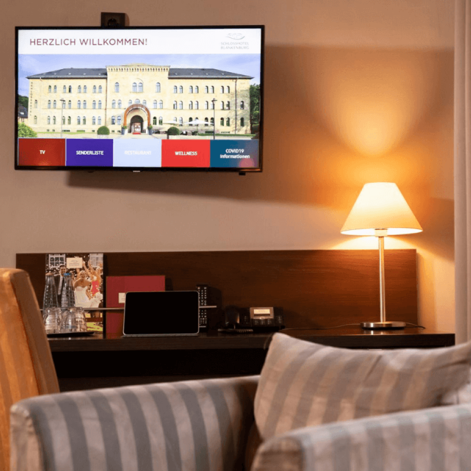 Blick auf den Schreibtisch mit TV und Stuhl vom Sessel aus