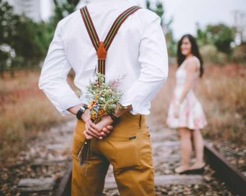 Mann mit Blumenstrauß hinter dem Rücken