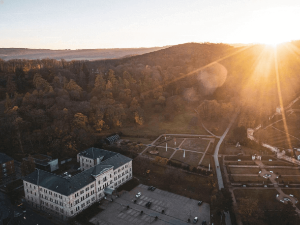 Ansicht von oben auf Hotelgebäude, Parkplatz und Landschaft bei Sonnenuntergang