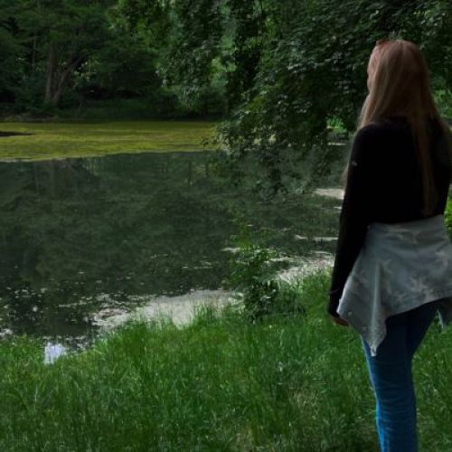 Frau steht vor einem See