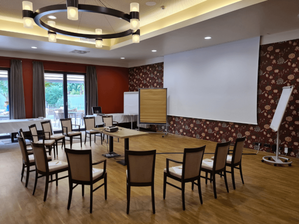 Schloss-Saal 1 mit Stuhlkreis, Leinwand, Flipchart, Beamer und Pinnwand