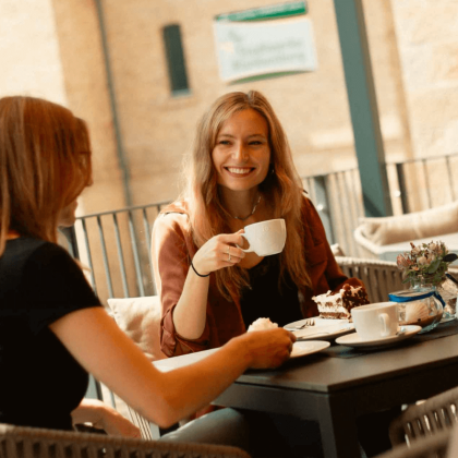 Gäste genießen Kaffee und Kuchen auf der sonnigen Schlossterrasse während ihres Frühlingsurlaubs in Blankenburg.